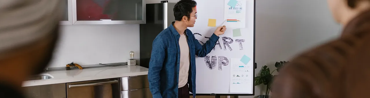 man in blue jacket looking at white board